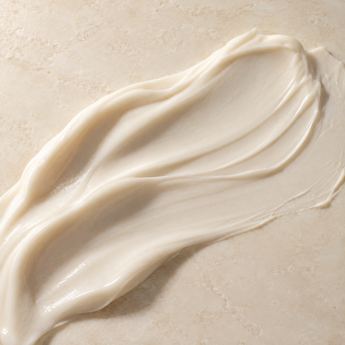 Textura cremosa marfil de la crema extendida sobre piedra clara